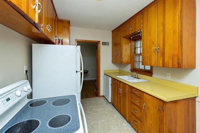 kitchen featuring sink, light tile patterned floors, and white appliances