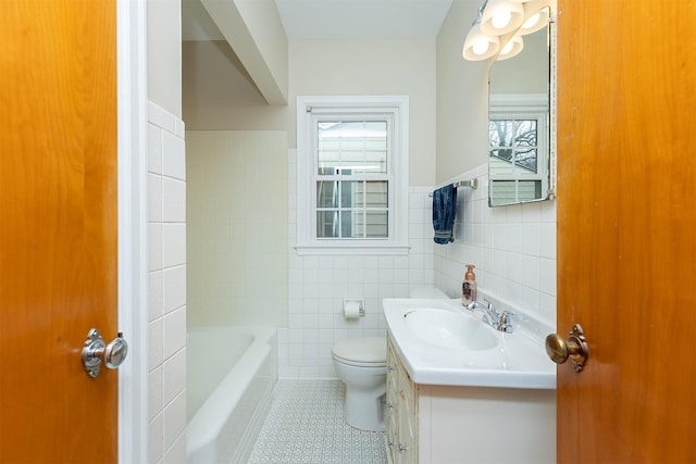 bathroom with a bath, tile patterned floors, toilet, vanity, and tile walls