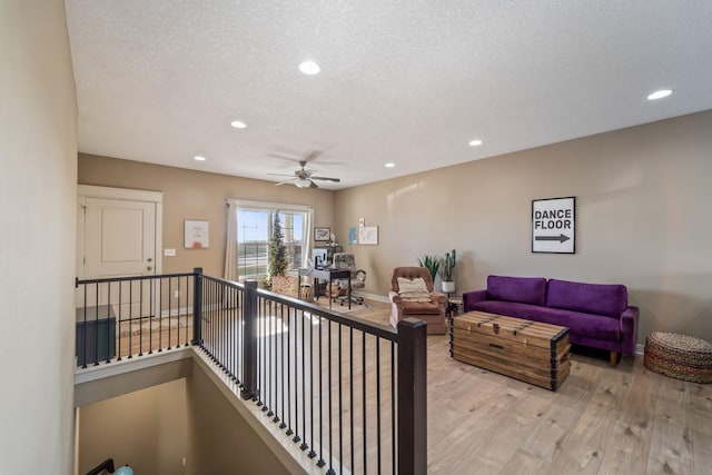 living room featuring a textured ceiling, light wood-type flooring, and ceiling fan