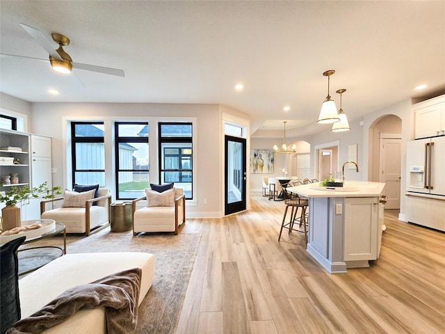 living room featuring ceiling fan with notable chandelier and light wood-type flooring