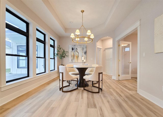 dining space featuring light hardwood / wood-style floors, a tray ceiling, and a notable chandelier