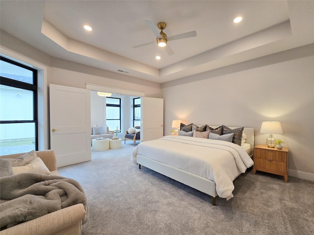 bedroom featuring ceiling fan, a raised ceiling, and carpet floors