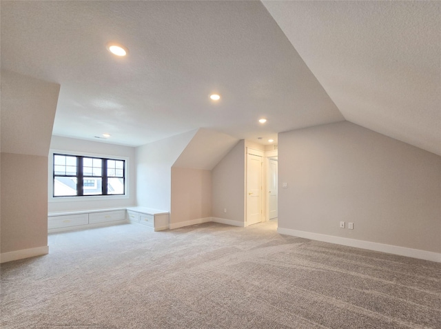 bonus room featuring a textured ceiling, light carpet, and vaulted ceiling