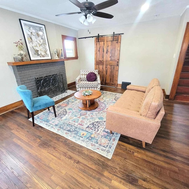 living room with dark hardwood / wood-style floors, ceiling fan, a barn door, and a fireplace