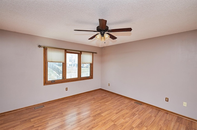 spare room with ceiling fan, a textured ceiling, and light wood-type flooring