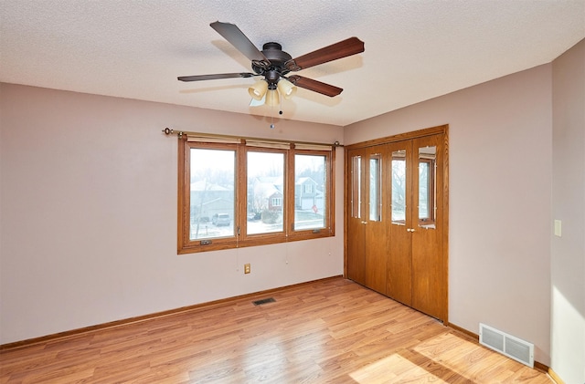 interior space featuring ceiling fan, light hardwood / wood-style floors, and a textured ceiling