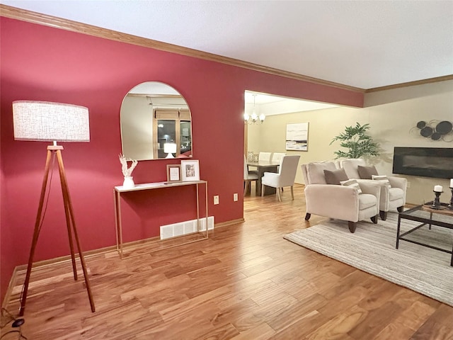 living room featuring crown molding, hardwood / wood-style floors, and a notable chandelier