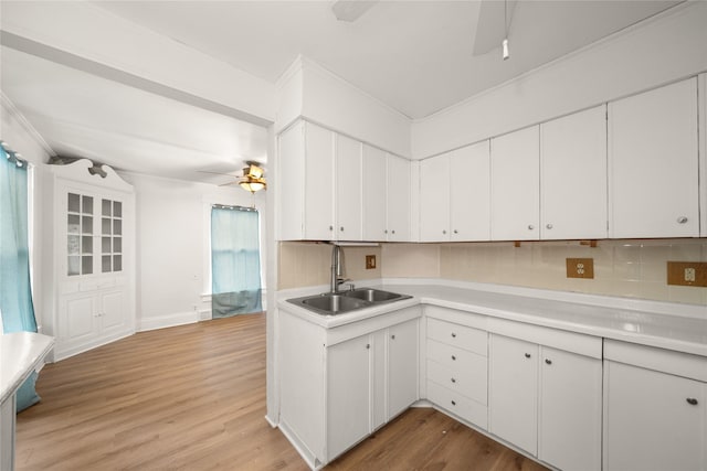 kitchen with decorative backsplash, white cabinetry, sink, and light wood-type flooring