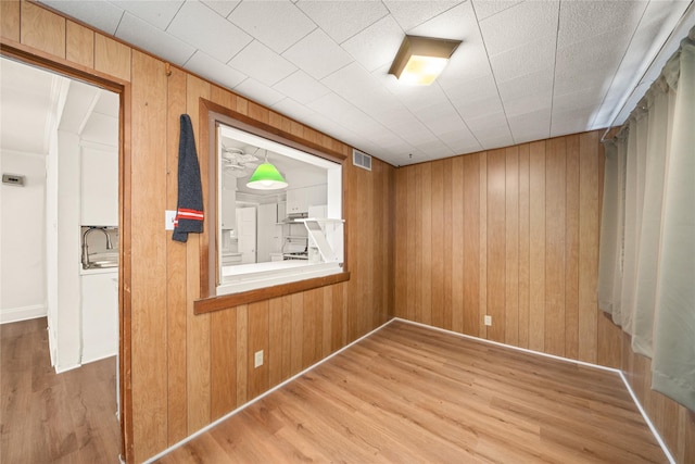 empty room featuring wooden walls and light hardwood / wood-style flooring