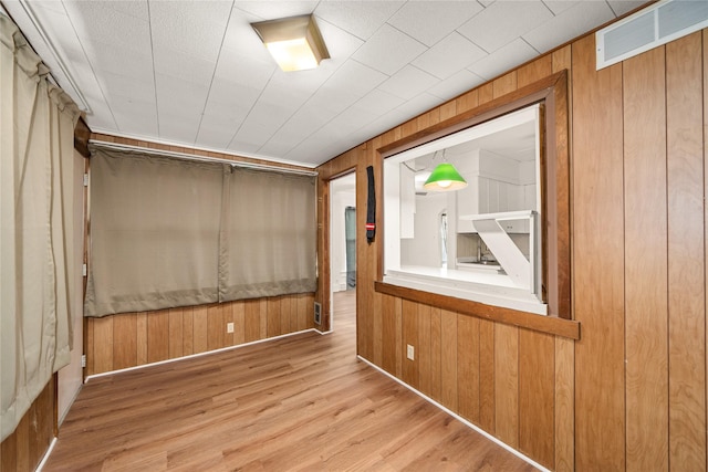 empty room featuring wooden walls and light hardwood / wood-style flooring