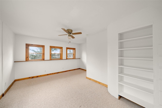 carpeted empty room with built in shelves and ceiling fan