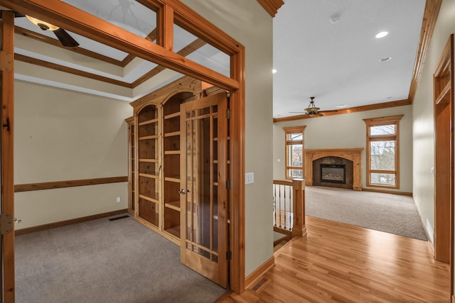 corridor with light hardwood / wood-style flooring and ornamental molding