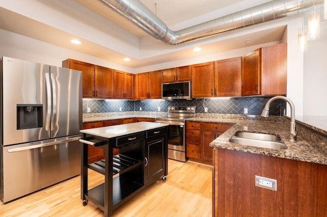 kitchen featuring dark stone countertops, sink, light wood-type flooring, and appliances with stainless steel finishes