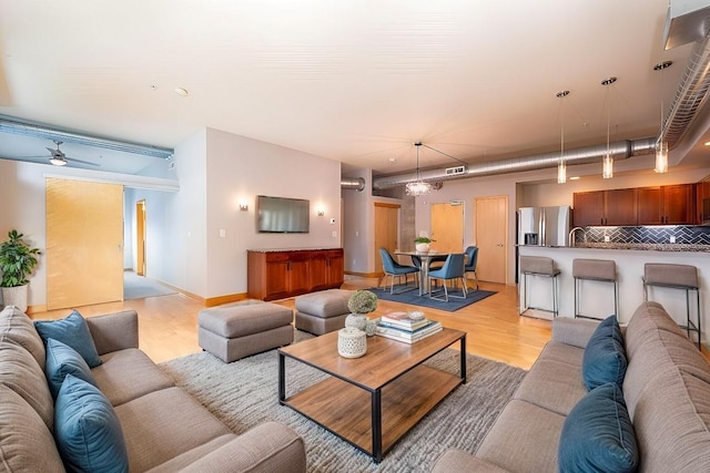 living room featuring ceiling fan with notable chandelier and light hardwood / wood-style floors