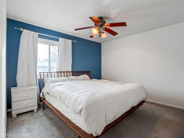 carpeted bedroom featuring ceiling fan and a textured ceiling