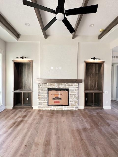 unfurnished living room featuring a fireplace, wood finished floors, and beam ceiling