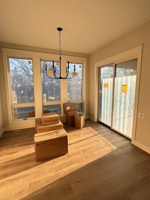 interior space featuring a chandelier, wood finished floors, and baseboards