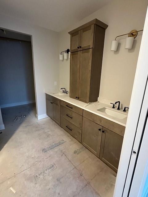 bathroom with double vanity, baseboards, and a sink