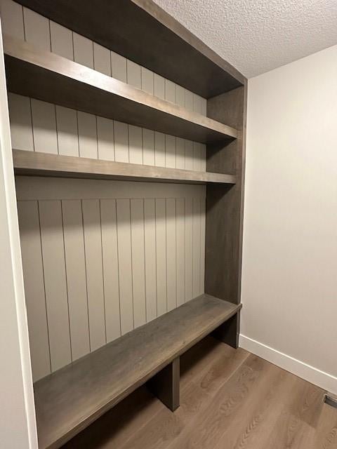 mudroom with a textured ceiling, wood finished floors, and baseboards