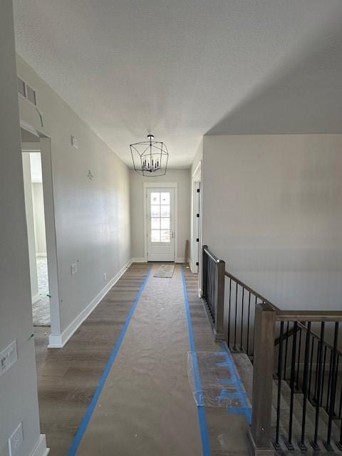 interior space with dark wood-style flooring, visible vents, baseboards, stairway, and an inviting chandelier