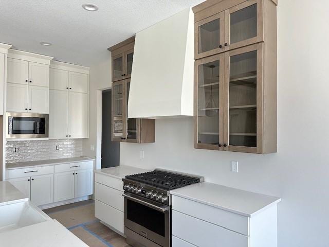 kitchen with white cabinets, glass insert cabinets, stainless steel appliances, and light countertops