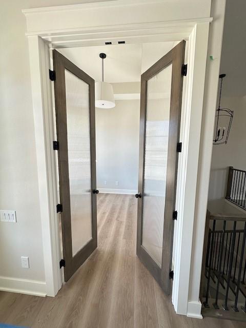 hall with french doors, wood finished floors, and baseboards