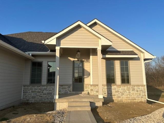 703 Richland Ct, Van Meter, IA 50261 - doorway to property featuring roof with shingles and stone siding