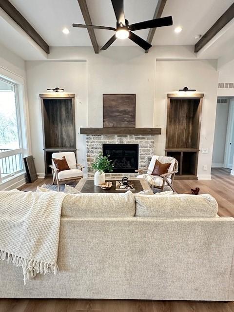 703 Richland Ct, Van Meter, IA 50261 - living area with wood finished floors, ceiling fan, a fireplace, beam ceiling, and visible vents
