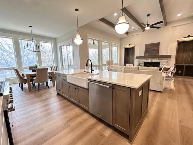 703 Richland Ct, Van Meter, IA 50261 - kitchen featuring light wood-style flooring, a sink, stainless steel appliances, light countertops, and a fireplace