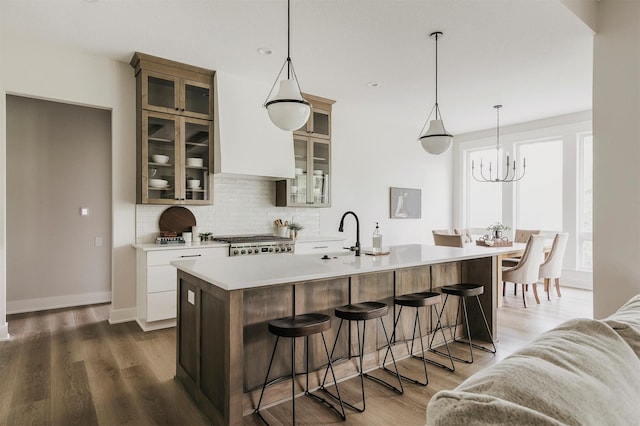 703 Richland Ct, Van Meter, IA 50261 - kitchen featuring decorative backsplash, light countertops, a kitchen bar, a chandelier, and wood finished floors