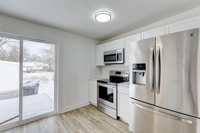 kitchen with white cabinetry, tasteful backsplash, a textured ceiling, appliances with stainless steel finishes, and light hardwood / wood-style floors