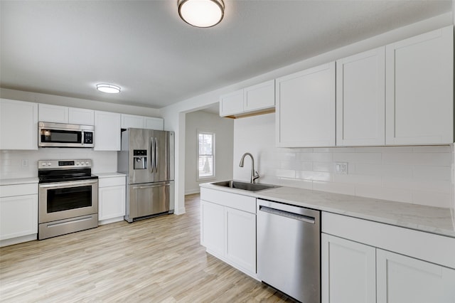 kitchen with white cabinetry, appliances with stainless steel finishes, sink, and light hardwood / wood-style flooring