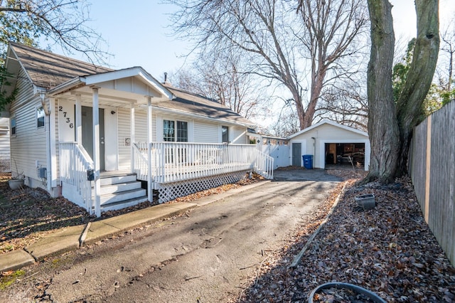 single story home featuring covered porch, a garage, and an outbuilding