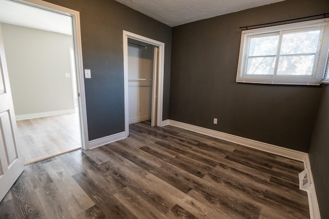 unfurnished bedroom with a closet and dark wood-type flooring