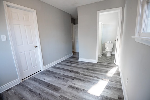 unfurnished bedroom featuring wood-type flooring and ensuite bath