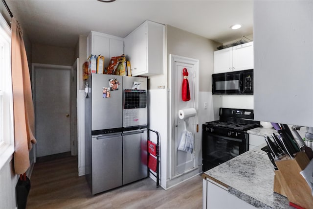 kitchen with white cabinets, light wood-type flooring, and black appliances