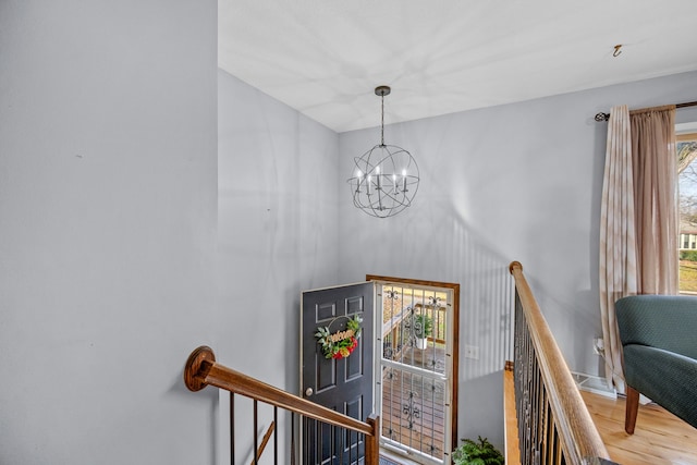 stairs featuring hardwood / wood-style flooring and an inviting chandelier