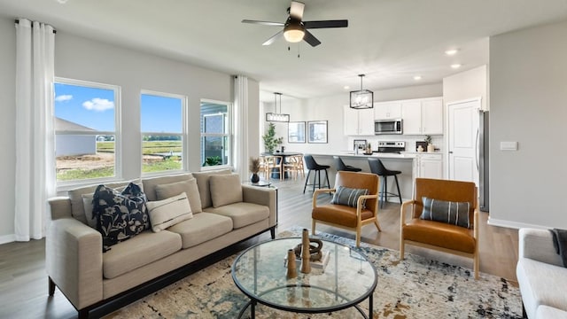 living area featuring recessed lighting, ceiling fan, baseboards, and wood finished floors