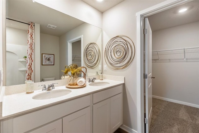 bathroom featuring double vanity, toilet, visible vents, and a sink