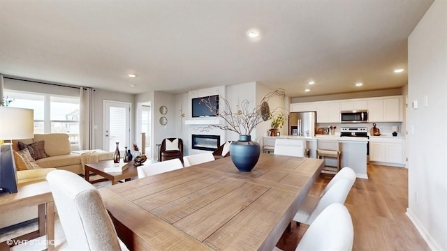 4772 172nd St, Urbandale, IA 50323 - dining room with light wood-style floors, a glass covered fireplace, and recessed lighting