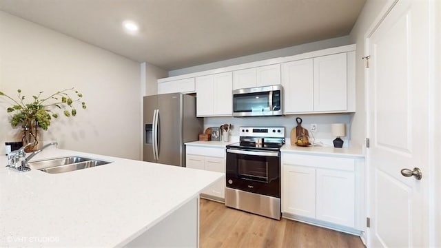 kitchen featuring white cabinets, sink, light wood-type flooring, and stainless steel appliances