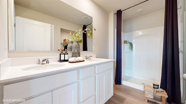 bathroom featuring wood-type flooring, vanity, and walk in shower