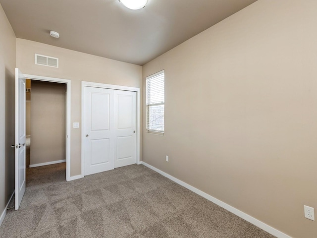 unfurnished bedroom featuring a closet and light colored carpet