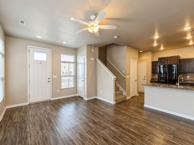 319 SW 7th St Unit 107, Des Moines, IA 50309 - kitchen featuring black refrigerator with ice dispenser, dark brown cabinets, dark wood-style floors, ceiling fan, and dark stone counters
