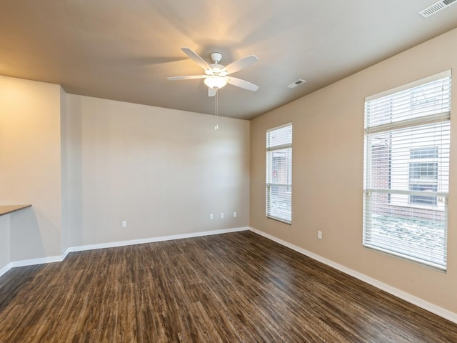 spare room with dark hardwood / wood-style flooring, a wealth of natural light, and ceiling fan