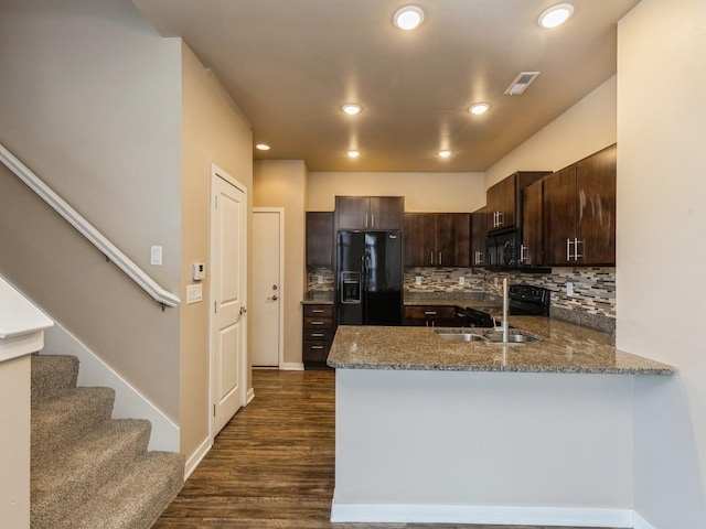 319 SW 7th St Unit 107, Des Moines, IA 50309 - kitchen featuring black appliances, dark brown cabinetry, stone counters, dark wood-style floors, and decorative backsplash