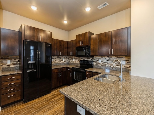 319 SW 7th St Unit 107, Des Moines, IA 50309 - kitchen featuring black appliances, dark brown cabinetry, dark wood-style flooring, decorative backsplash, and dark stone countertops