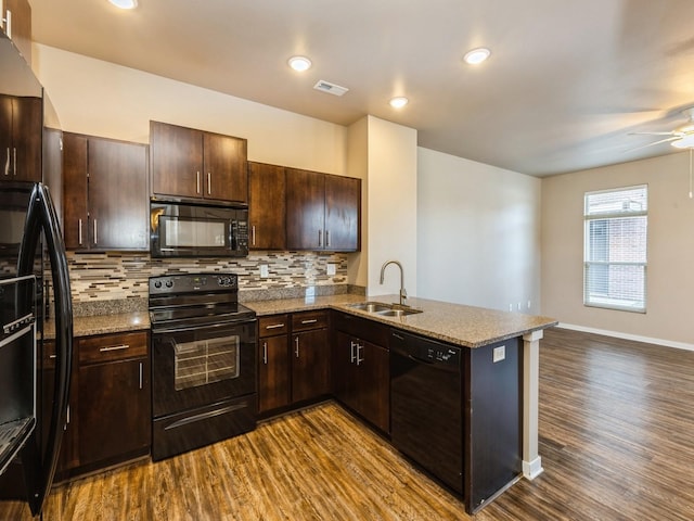 319 SW 7th St Unit 107, Des Moines, IA 50309 - kitchen featuring black appliances, dark wood-style flooring, a peninsula, decorative backsplash, and dark brown cabinetry