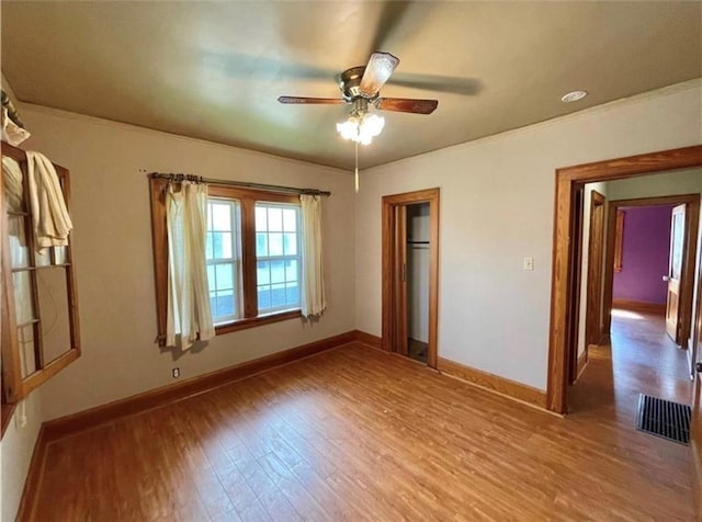 unfurnished bedroom featuring ceiling fan, wood-type flooring, crown molding, and a closet