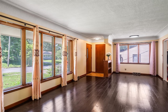 doorway to outside featuring a healthy amount of sunlight, dark hardwood / wood-style flooring, and a textured ceiling